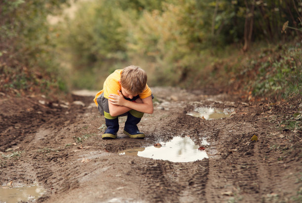 男孩看了看乡间路上的水坑图片下载