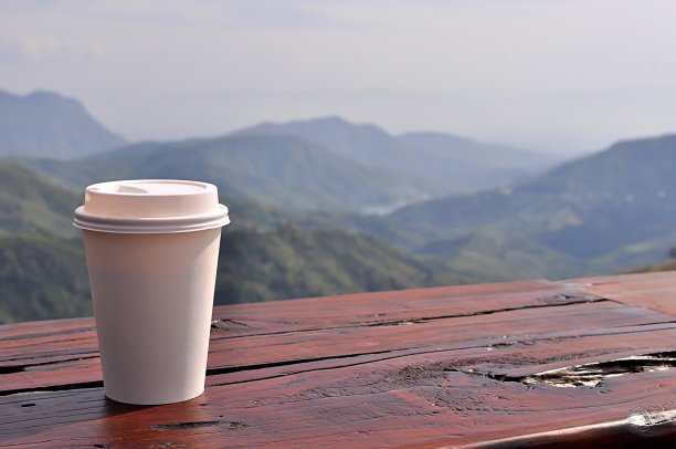 白色杯子里的咖啡，背后是自然风景。图片下载