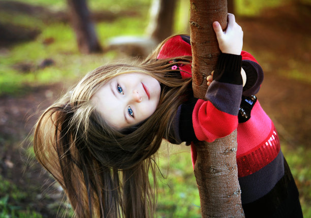 微笑的小女孩在大自然中抱住树图片下载