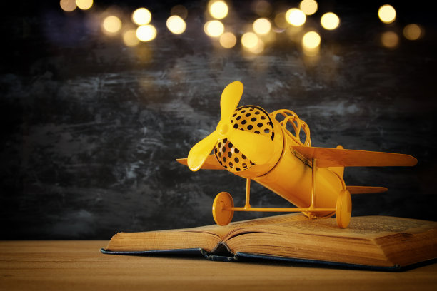 玩具飞机和我打开的书在木桌上。图片下载