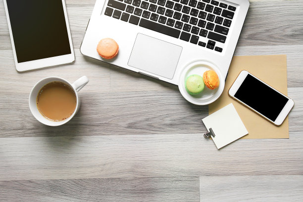 俯视图的工作空间与马卡龙和咖啡休息时间，笔记本电脑，平板电脑，智能手机。办公室的桌子上。图片下载