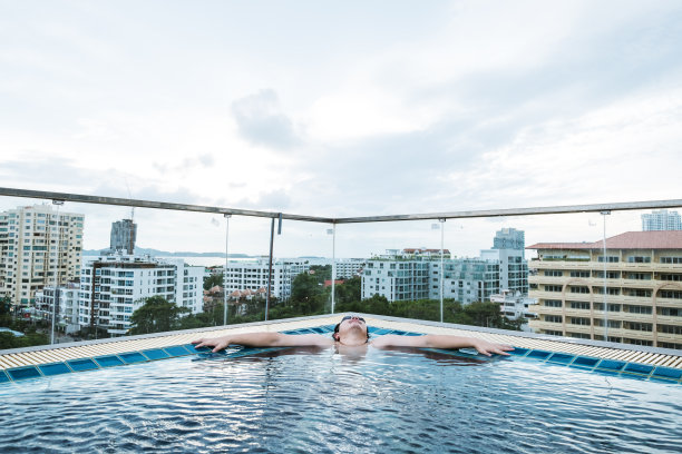 在游泳池中放松，以城市景观为背景图片下载
