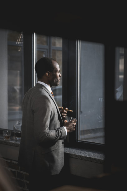 沉思的非裔美国商人西装，一杯威士忌，抽着雪茄图片下载