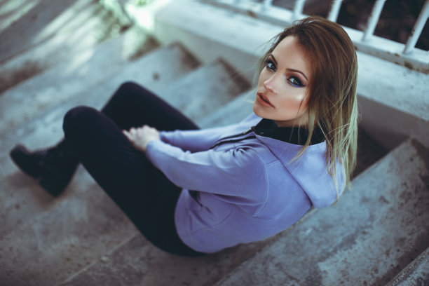 穿着帽衫的金发美女坐在水泥台阶上图片下载