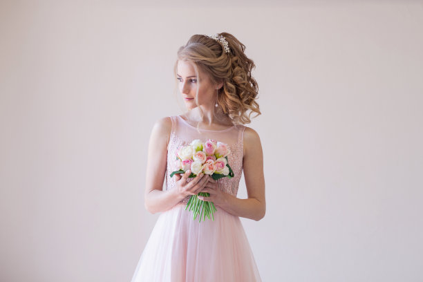 新娘身着粉色婚纱，捧着一束鲜花图片下载