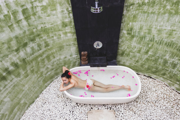 女人放松在圆形户外沐浴热带鲜花，有机皮肤护理，豪华水疗酒店，生活方式照片图片下载