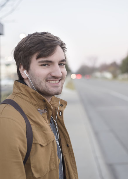 迷人的年轻人微笑着等公共汽车图片下载