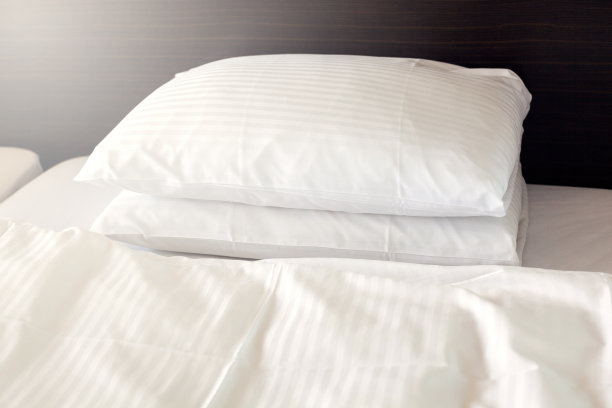 白色的枕头和毯子在闪亮的酒店卧室，在舒适的休息和午睡图片下载