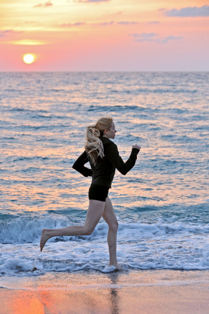 可爱的金发女慢跑海滩在日出图片下载