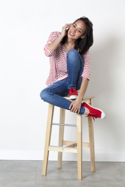 放松的20多岁混血女孩在手机上微笑图片下载