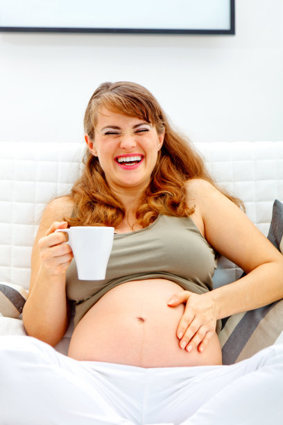 孕妇坐在沙发上，端着一杯茶图片下载