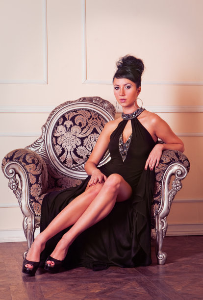 年轻的黑发女人穿着黑衣服坐在沙发上图片下载