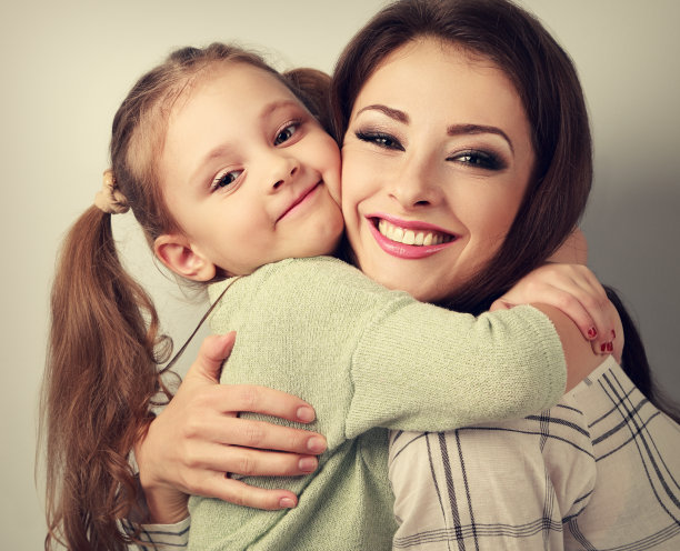 快乐微笑的母亲拥抱顽皮的情绪的小女孩在stud图片下载