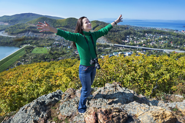年轻女子带着相机站在岩石上图片下载