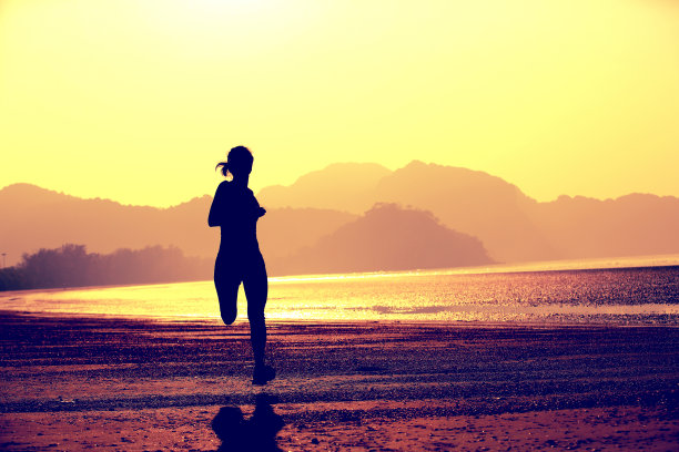 年轻的健身女性在海滩上跑步图片下载