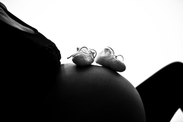 婴儿鞋在她母亲怀孕的肚子上图片下载