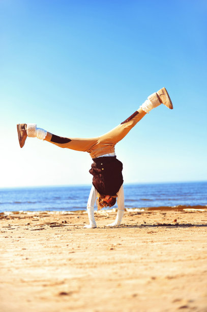 快乐的孩子在阳光明媚的沙滩上翻跟斗图片下载