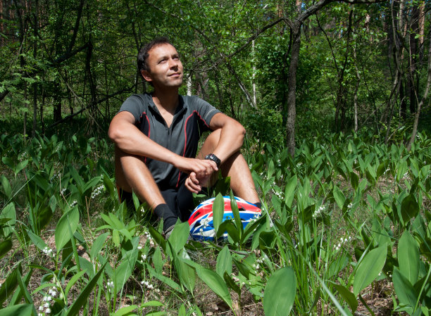 在松柏树下的针叶林里放松的自行车手图片下载