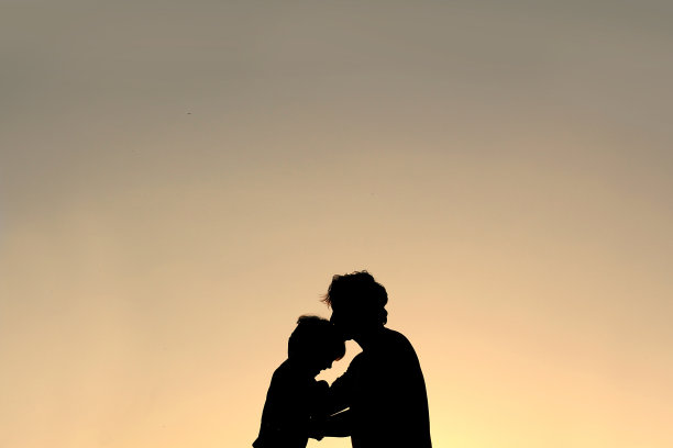 父亲亲吻孩子前额的剪影图片下载