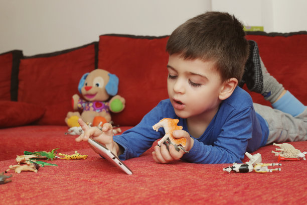 男孩在室内玩平板电脑图片下载