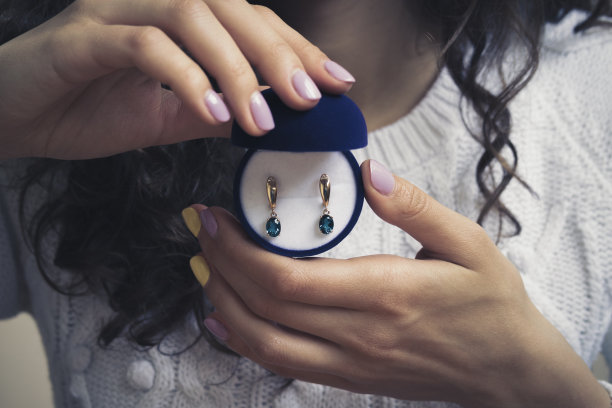 女人手上戴着蓝色黄玉的金耳环图片下载