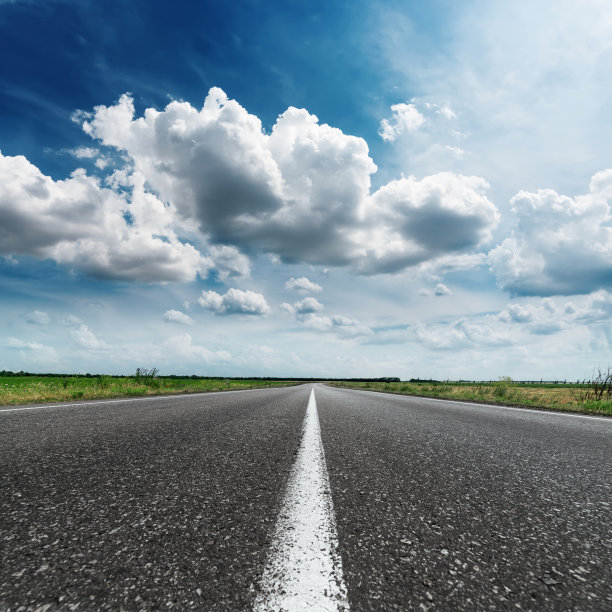 在引人注目的天空下，有白线的柏油路图片下载
