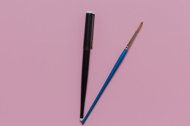 钢笔和画笔在粉红色的背景图片下载