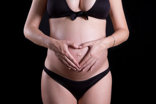 一个可爱的怀孕的腹部与黑色背景的特写图片下载