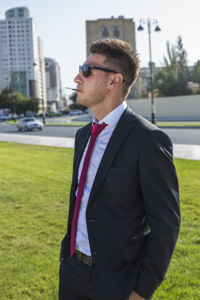 穿着西装，戴着眼镜，打着红领带的年轻商人。图片下载