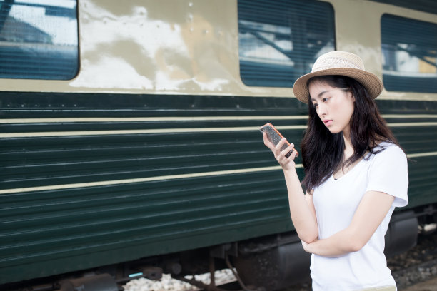 一名亚洲女性在火车站用智能手机发短信图片下载