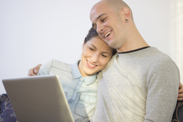 快乐的年轻夫妇，用笔记本电脑，微笑着。图片下载