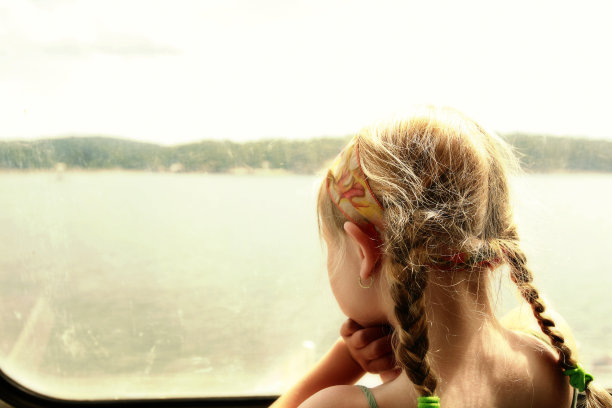 一个小女孩从船窗往外看。图片下载