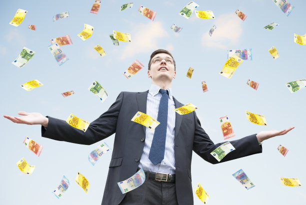 快乐的商人站在金钱的雨中图片下载