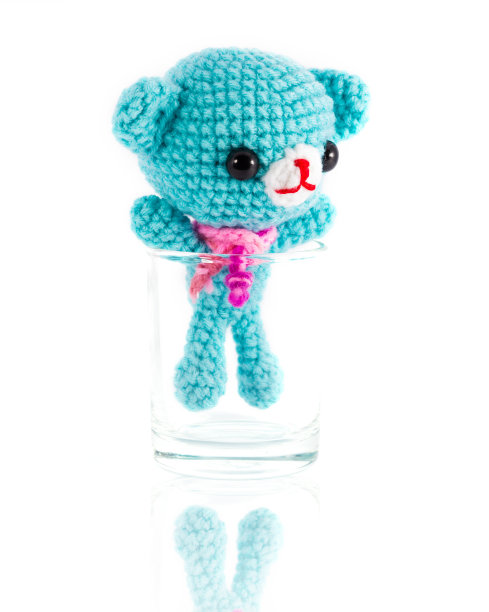 手工编织的蓝色熊娃娃在伏特加玻璃图片下载
