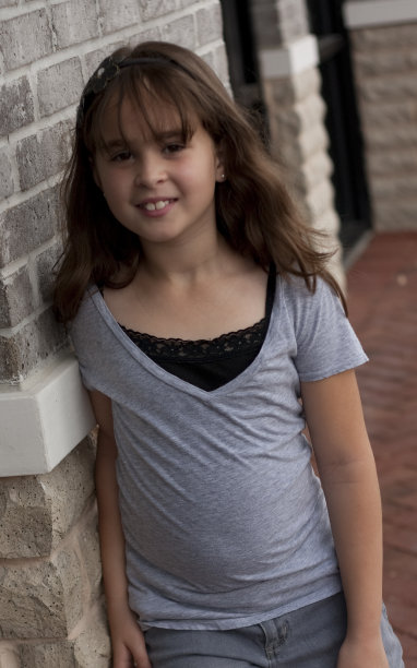 一个黑发姑娘靠在砖墙上图片下载