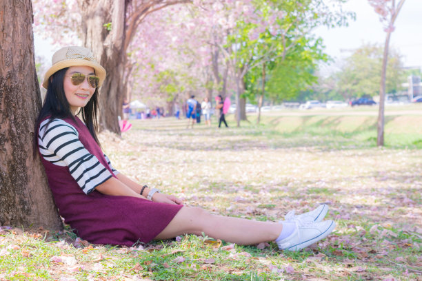 女亚洲游客帽子看到粉红色的喇叭树和天空图片下载