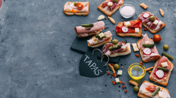 典型的西班牙小吃概念。概念包括各种各样的火腿片，西班牙香肠，意大利腊肠，碗橄榄，辣椒，凤尾鱼，辣土豆素材图片