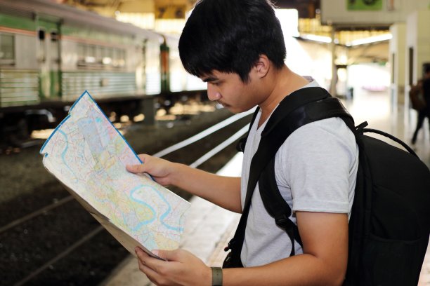 在火车站背景下寻找探索地图的青年游客脸部选择性聚焦。旅游的概念图片下载