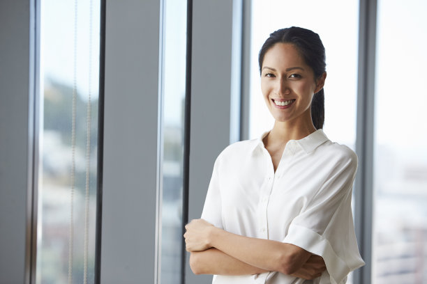 女商人站在办公室窗户旁的肖像图片下载