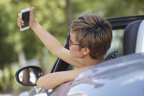 年轻的中国女子在一辆敞篷车里拍照图片下载