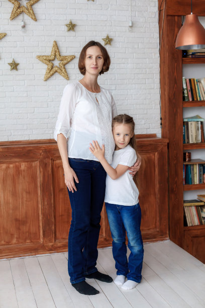 在影棚里拥抱怀孕妈妈的可爱小女孩图片下载