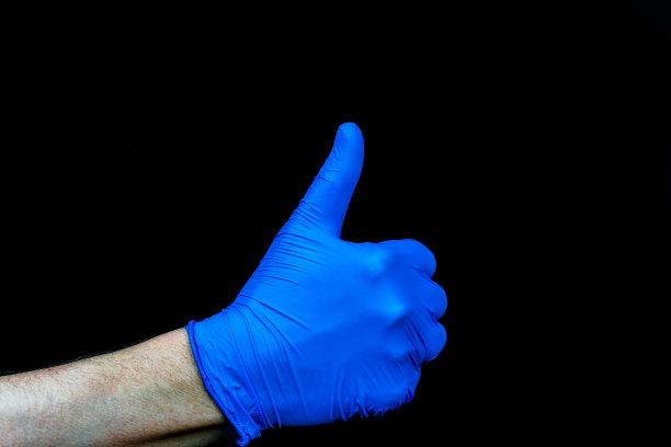 竖起大拇指。手戴蓝色医疗手套。图片下载