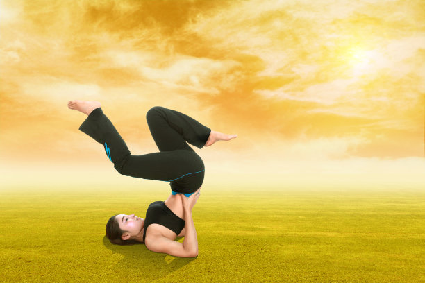 女人做瑜伽运动在草地上与天空在日落图片下载