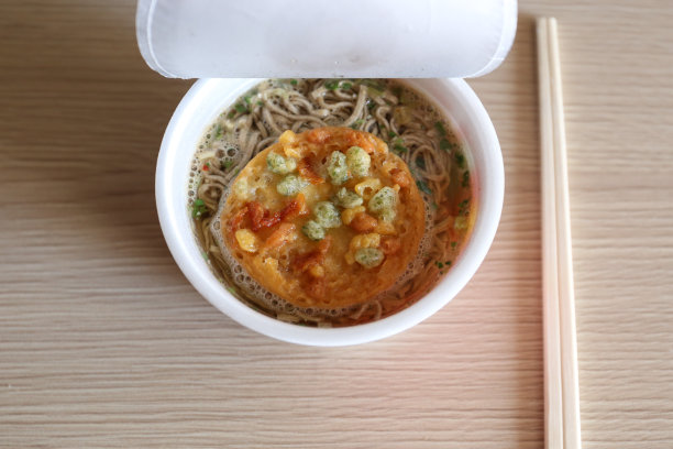 白色泡沫杯上放有配料的方便面，木桌上放有筷子图片下载