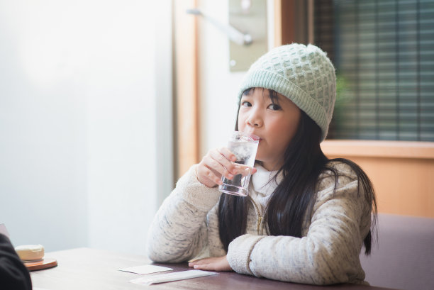 一个亚洲女孩在餐厅里喝一杯水图片下载