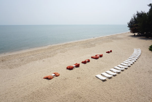 白色沙滩床和白色塑料桌子在沙滩上图片下载