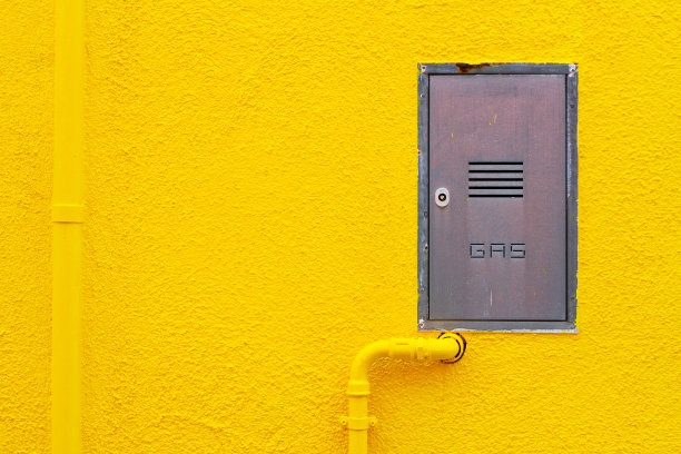 煤气管道和技术舱口在亮黄色的灰泥墙上图片下载