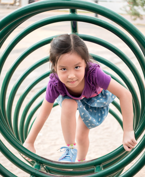 快乐的小朋友，亚洲宝宝在操场上玩耍，爬上操场上的器材，圆的形状图片下载