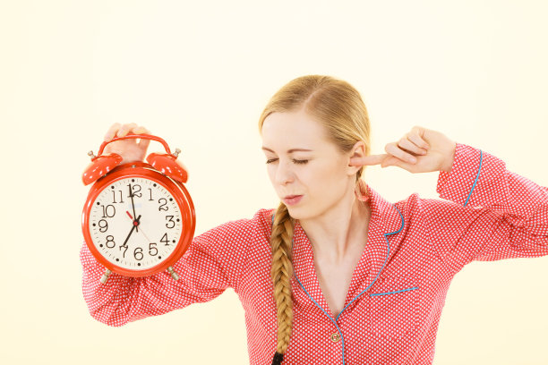 睡眼惺忪的女人穿着睡衣拿着钟图片下载