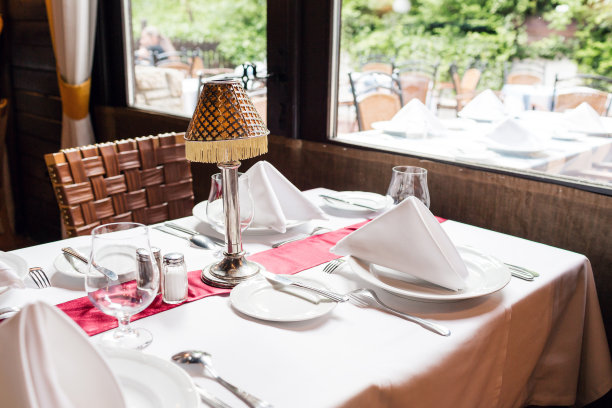 为甜蜜晚餐准备的餐桌。餐厅里的空杯子。内部的一部分。餐巾、盘子和餐具。图片下载